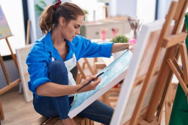 Young woman artist looking draw with doubt expression at art studio