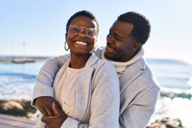 Erkek ve kadın çift sahilde birbirlerine sarılıyorlar.