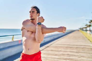 Young man stretching arms at seaside