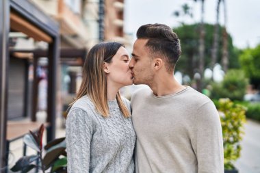 Man and woman couple hugging each other kissing at street