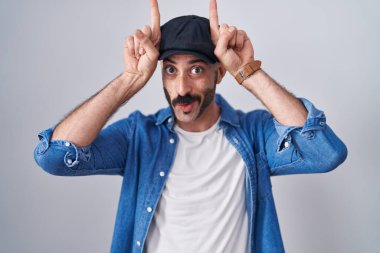 Sakallı İspanyol bir adam izole edilmiş arka planda duruyor ve parmağıyla boynuz gibi hareket ediyor. 