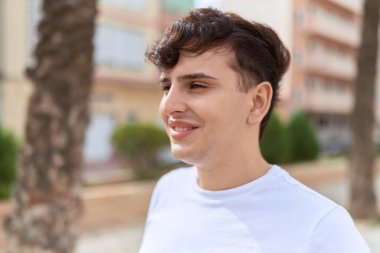 Non binary man smiling confident looking to the side at park