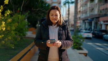 Mother and daugthers using smartphone standing together at park