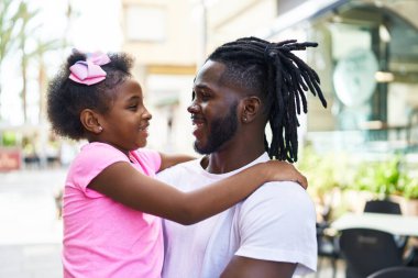 Father and daughter smiling confident hugging each other at coffee shop terrace