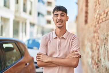 Sokakta kollarını kavuşturmuş İspanyol genç bir adam.