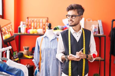 Genç İspanyol terzi atölyedeki defterde kendinden emin bir şekilde yazıyor.