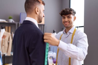 Two hispanic men tailor measuring chest client at atelier