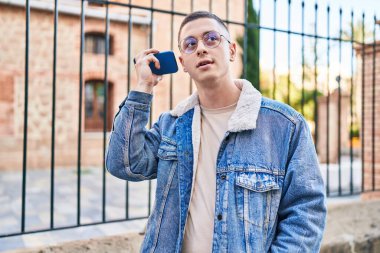 Genç İspanyol adam caddedeki akıllı telefondan sesli mesaj dinliyordu.