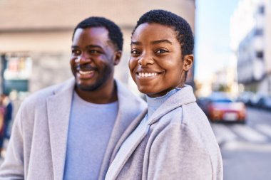 Erkek ve kadın bir arada durarak gülümsüyor.