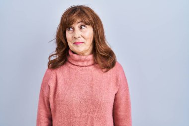 Orta yaşlı İspanyol bir kadın soyutlanmış arka planda duruyor gülümsüyor ve yan tarafa bakıyor.. 