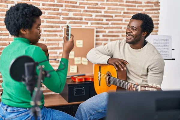African american man and woman music group make photo holding spanish guitar at music studio