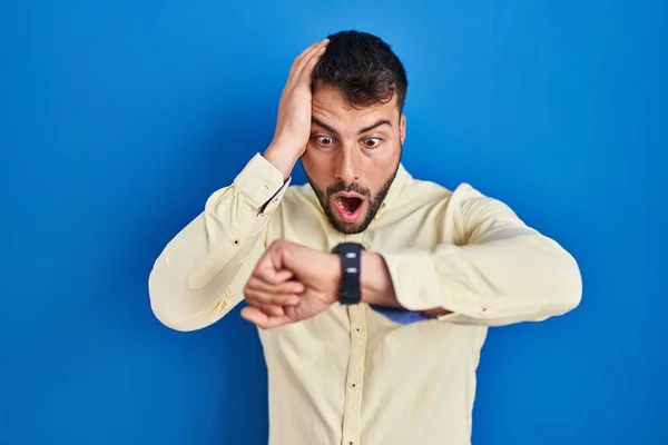 Handsome Hispanic Man Standing Blue Background Looking Watch Time Worried — Stock Photo, Image