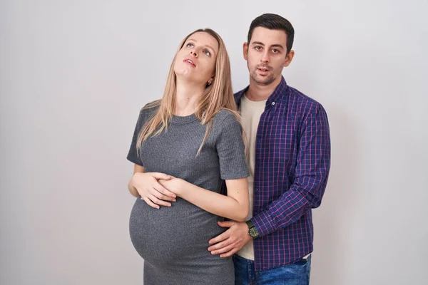 Casal Jovem Esperando Bebê Sobre Fundo Branco Olhando Sonolento Cansado — Fotografia de Stock