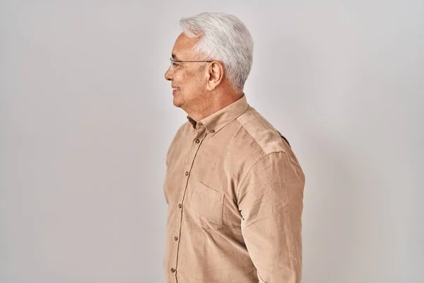 Hispanic senior man wearing glasses looking to side, relax profile pose with natural face with confident smile.