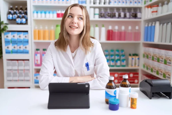 Young Caucasian Woman Working Pharmacy Drugstore Using Tablet Looking Away — Foto Stock