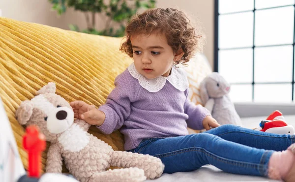 可爱的惊慌失措的女孩和泰迪熊坐在沙发上 — 图库照片
