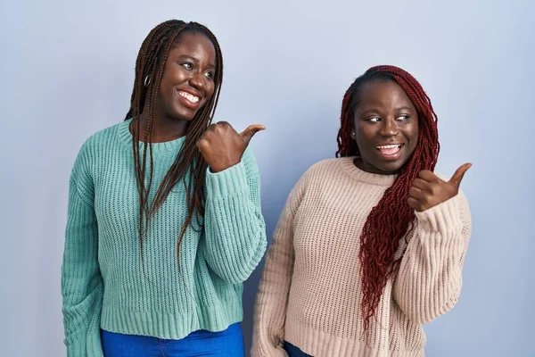 Две Африканки Стоящие Над Синим Фоном Улыбающиеся Счастливым Лицом Смотрящие — стоковое фото