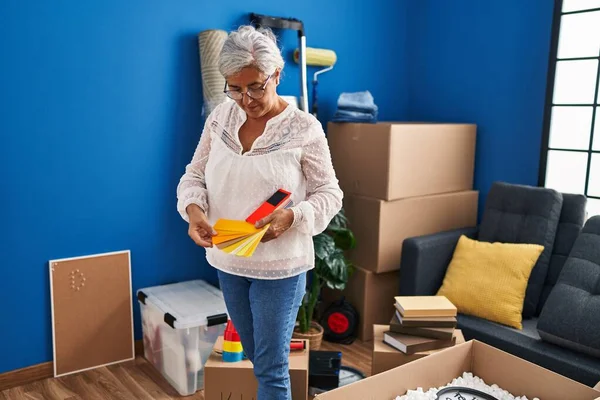 Middle age woman choosing test paint color at new home