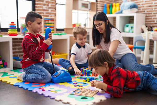 Teacher with group of boys playing with toys sitting on floor at kindergarten