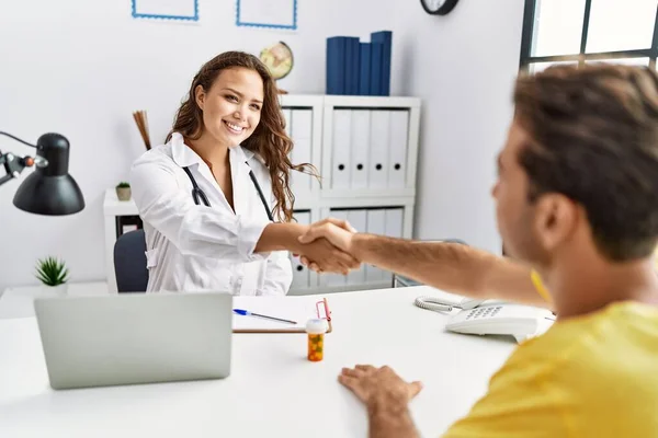 Man and woman having doctor visit shake hands at clinic