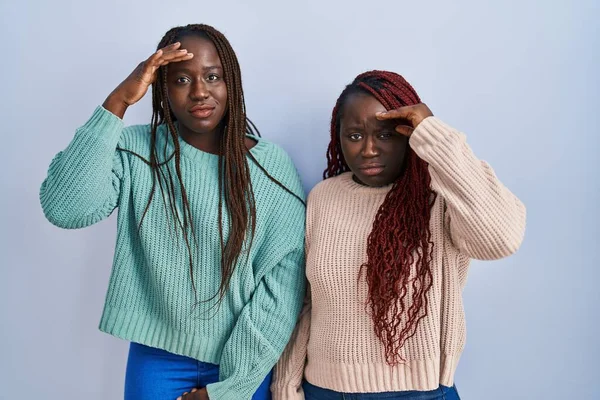 青い背景の上に立っている2人のアフリカ人女性は 額に手で問題を心配し 緊張し 危機を切望していました — ストック写真