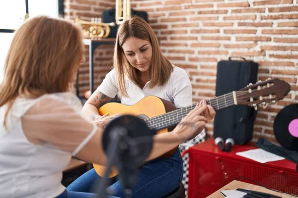 Mother and daughter musicians having spanish guitar class at music studio
