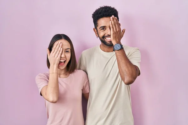 Junge Hispanische Paar Zusammen Über Rosa Hintergrund Bedeckt Ein Auge — Stockfoto