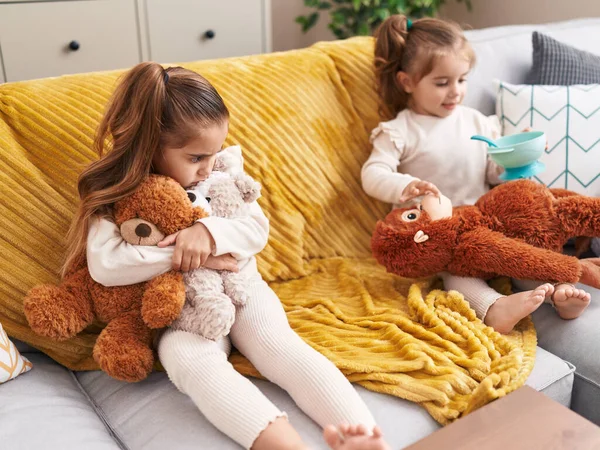 Dvě Děti Hrají Panenkami Sedícími Doma Gauči — Stock fotografie