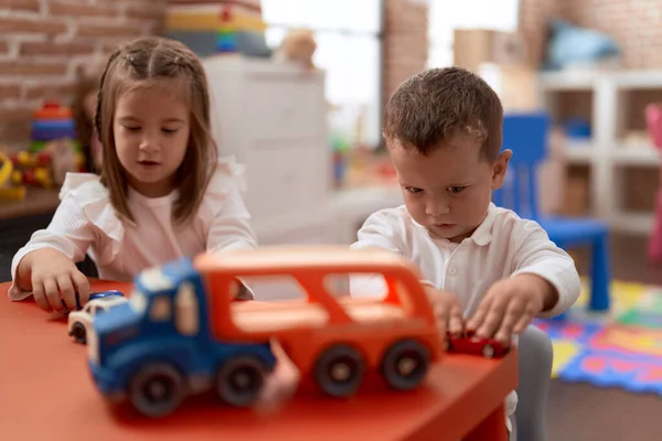 愛らしい女の子と男の子遊びますおもちゃとともにテーブルの上に幼稚園 — ストック写真