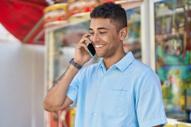 African american man smiling confident talking on the smartphone at street market