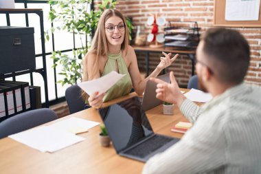 Kadın ve erkek işçiler ofiste dizüstü bilgisayar kullanıyorlar.