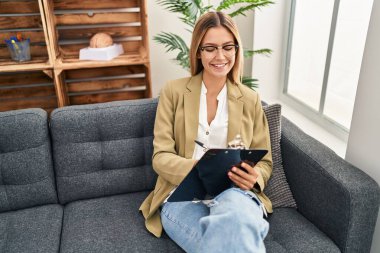 Psikoloji merkezindeki kanepede oturan genç İspanyol psikolog zihinsel rapor yazıyor.