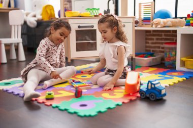 Two kids playing xylophone sitting on floor at kindergarten