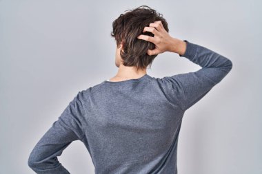 İzole edilmiş arka planda duran genç adam elleri başının üstünde şüpheyi düşünüyor. 