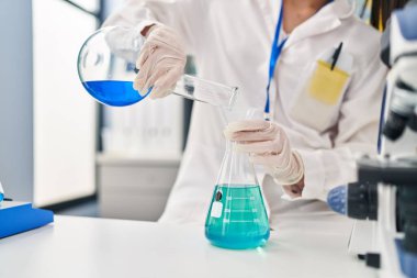 Genç ve güzel İspanyol bilim kadını laboratuarda test tüpüne sıvı döküyor.