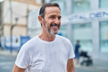 Middle age man smiling confident looking to the side at street