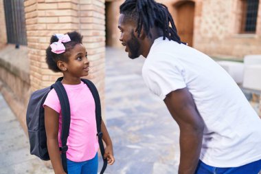 Father and daughter standing together speaking at school