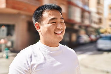 Young chinese man smiling confident standing at street
