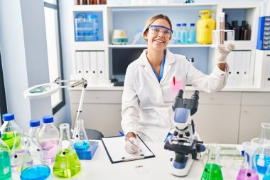 Genç İspanyol kadın bilim adamı, laboratuardaki test tüplerini tutan belgelere yazı yazmış.