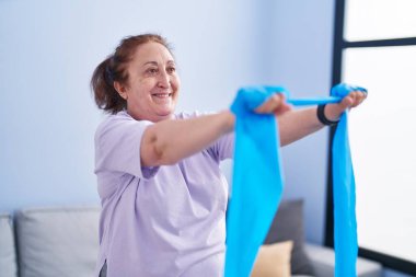 Senior woman smiling confident using elastic band training at home