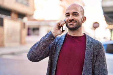 Genç adam gülümsüyor. Kendine güveniyor. Sokakta akıllı telefondan konuşuyor.