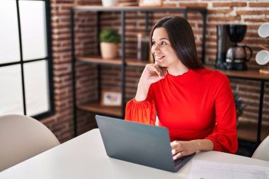 Evdeki masada dizüstü bilgisayar kullanan güzel bir İspanyol kadın.