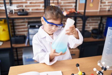 Adorable hispanic girl student holding test tube at laboratory classroom