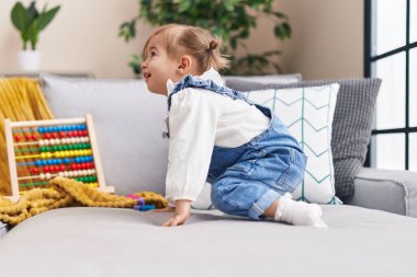 Abaküsle oynayan sevimli sarışın çocuk evdeki kanepede oturuyor.