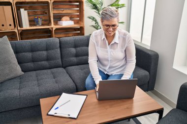 Orta yaşlı kadın psikolog, pischoloji merkezindeki koltukta oturuyor.
