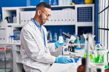 African american man scientist smiling confident weighing pills at laboratory