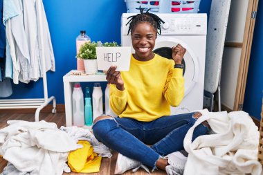 Güzel siyah kadın çamaşırlarını yıkıyor gururla yardım istiyor zaferi kutluyor ve kollarını kaldırarak heyecanlanıyor. 