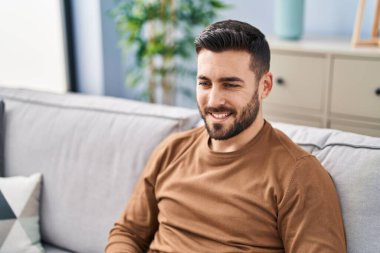 Evdeki kanepede kendinden emin gülümseyen İspanyol genç adam.