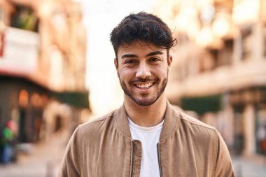 Sokakta kendinden emin gülümseyen İspanyol genç adam.