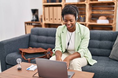 African american woman doing online session at consultation office looking positive and happy standing and smiling with a confident smile showing teeth 